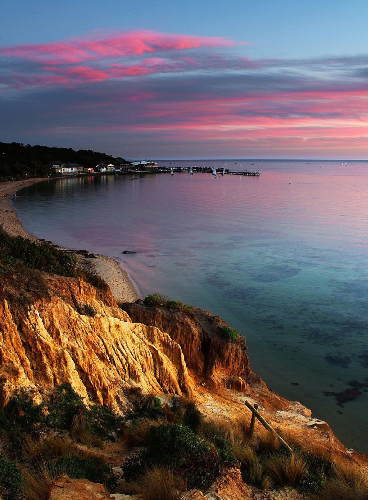Warm evening light over the red cliffs and sheltered water of Half Moon Bay
